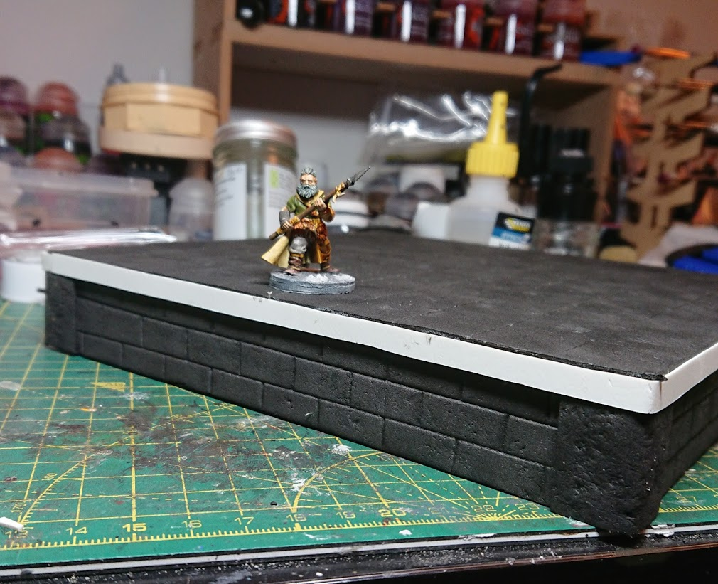 A Frostgrave barbarian on a complete, but unpainted square riser 