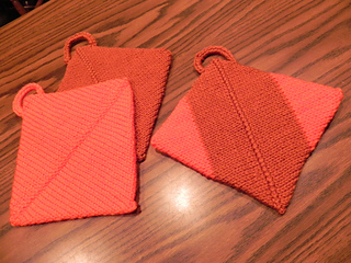 three knit hot pads on wooden table