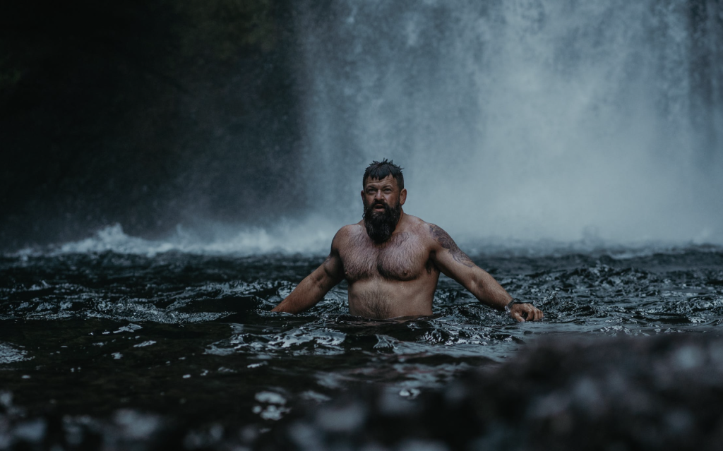 Man swimming under waterfull