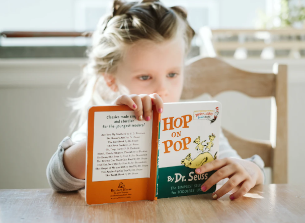 a little girl reading a Dr Seuss book