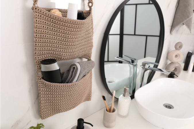 A nicely organized bathroom counter with hanging storage baskets and a decorative toothbrush cup.