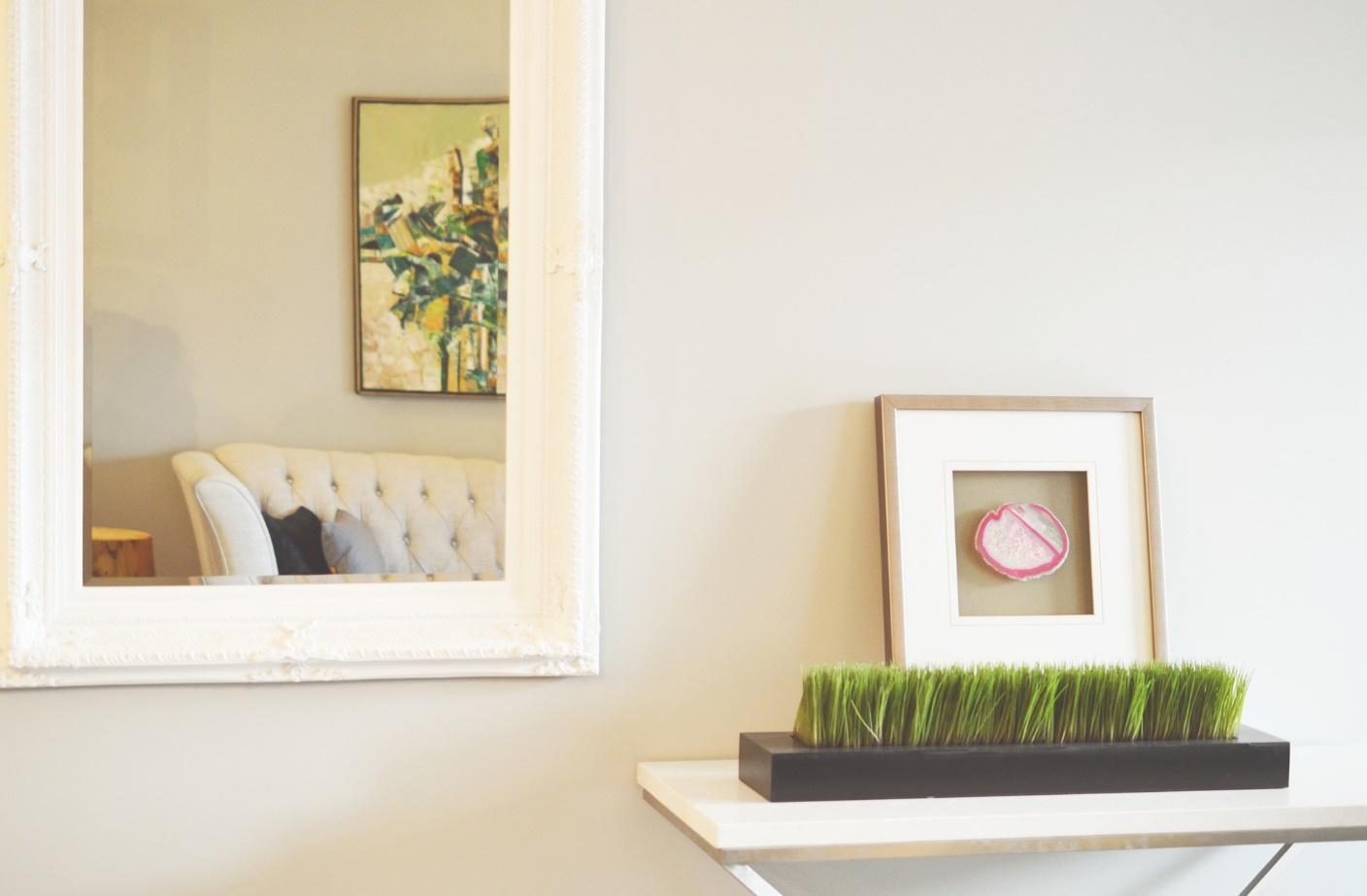 A mirror in a white frame with a shelf next to it.