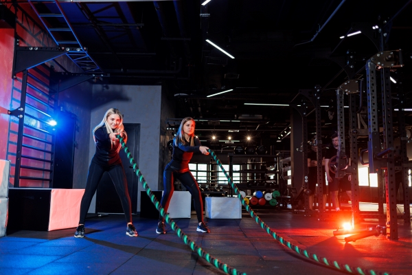 two-young-women-exercising-with-ropes-ropes-gym-woman-doing-rope-workout-together-with-trainer