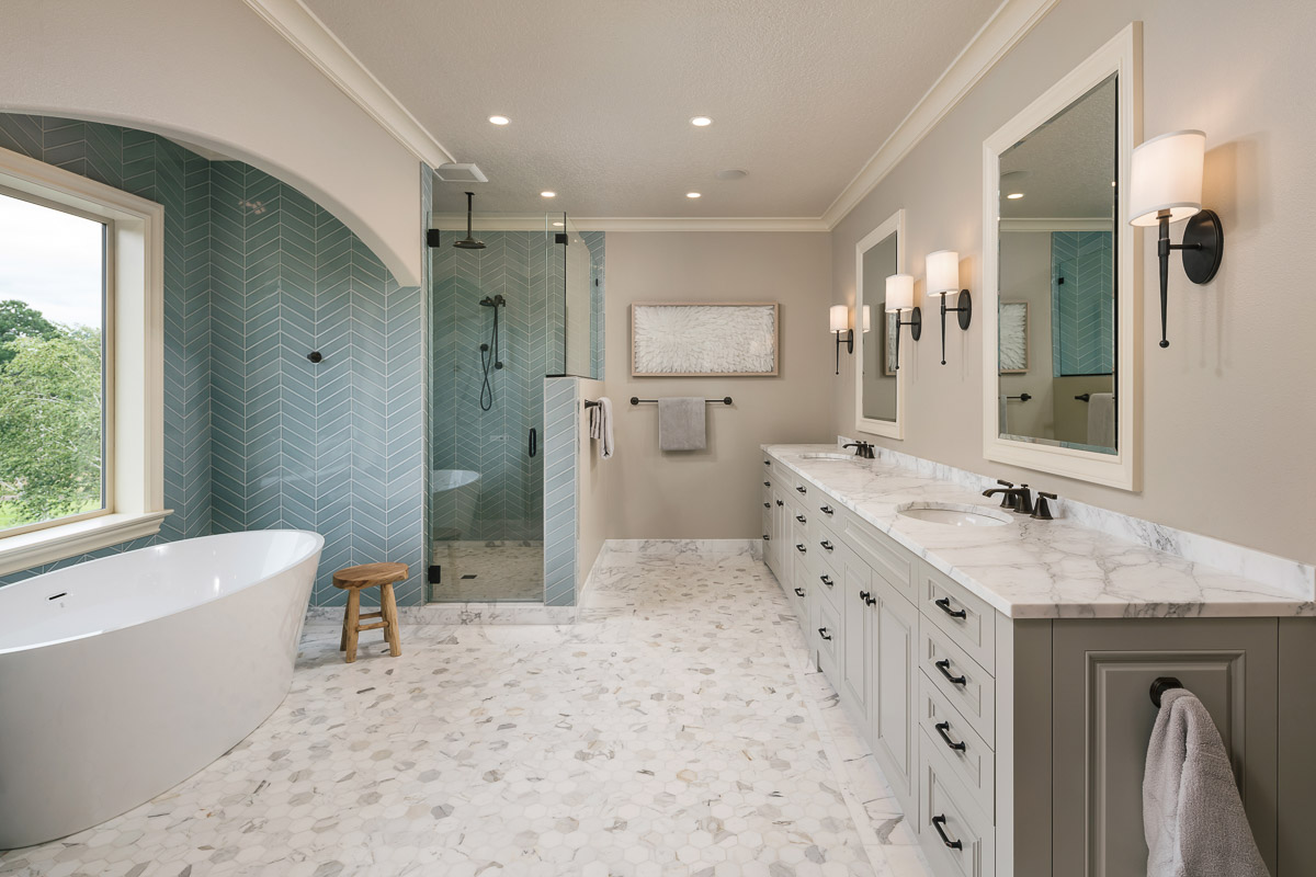 large master bathroom with bathtub, shower, two sinks, marble flooring, and blue backsplash