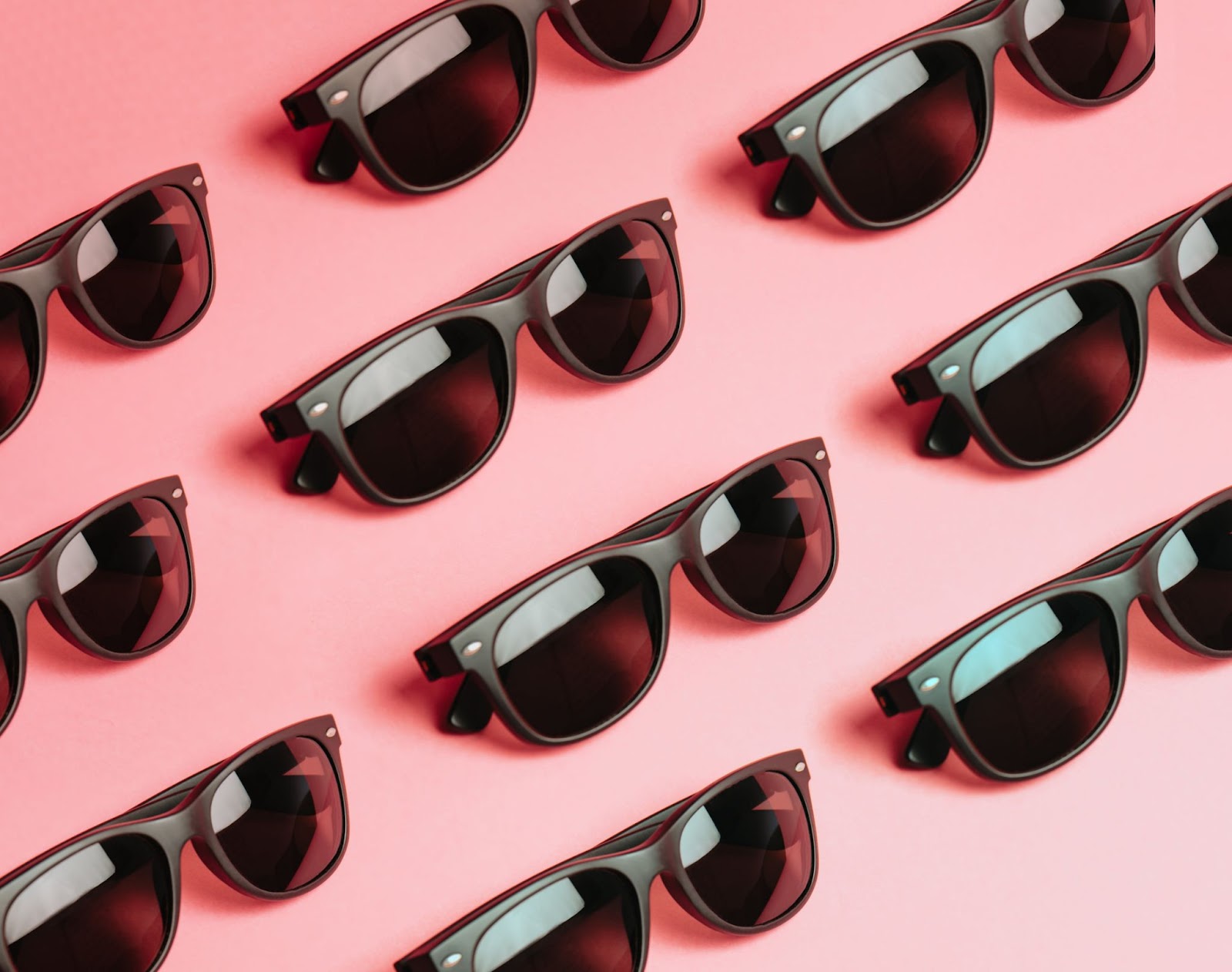 A lineup of black-framed glasses on a pink background 