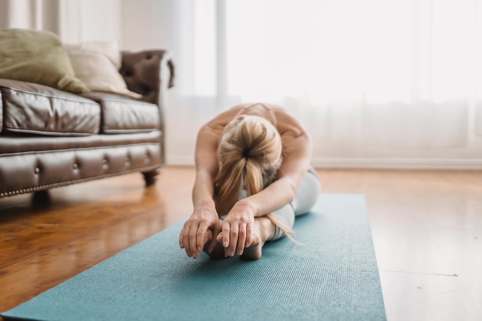 Femme blonde faisant des étirements sur un tapis de Yoga afin de soulager le dos