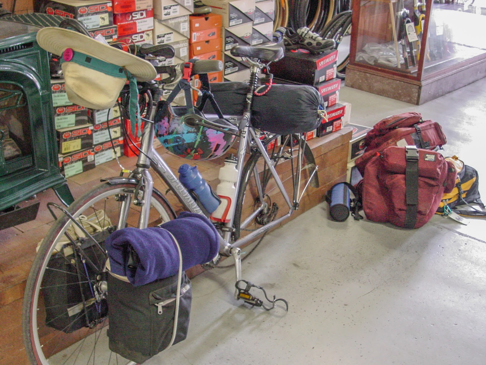 Bicycle with no back wheel and bags on the floor of a shop.