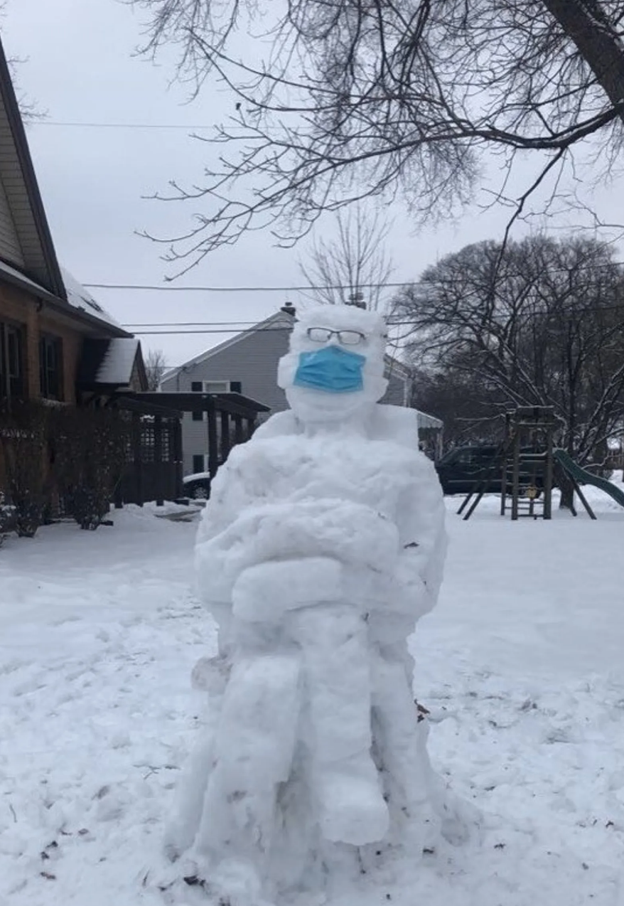 Snow sculpture of masked man sitting cross legged 