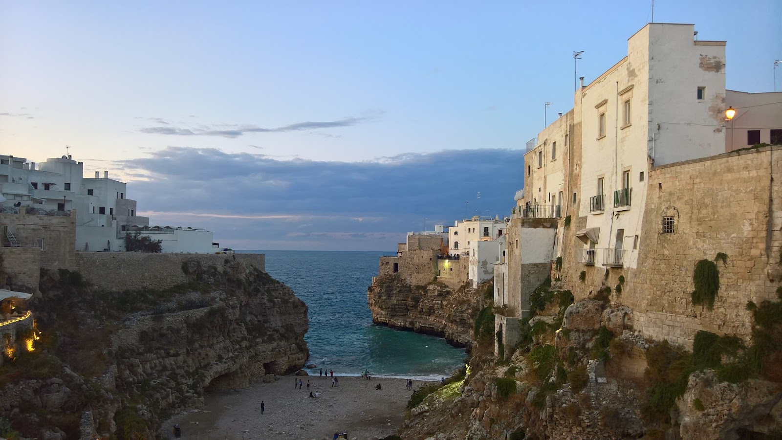 beautiful small italian sandy beach surrounded by whitewashed buildings and cliffs blue sea near bari south of italy sunset