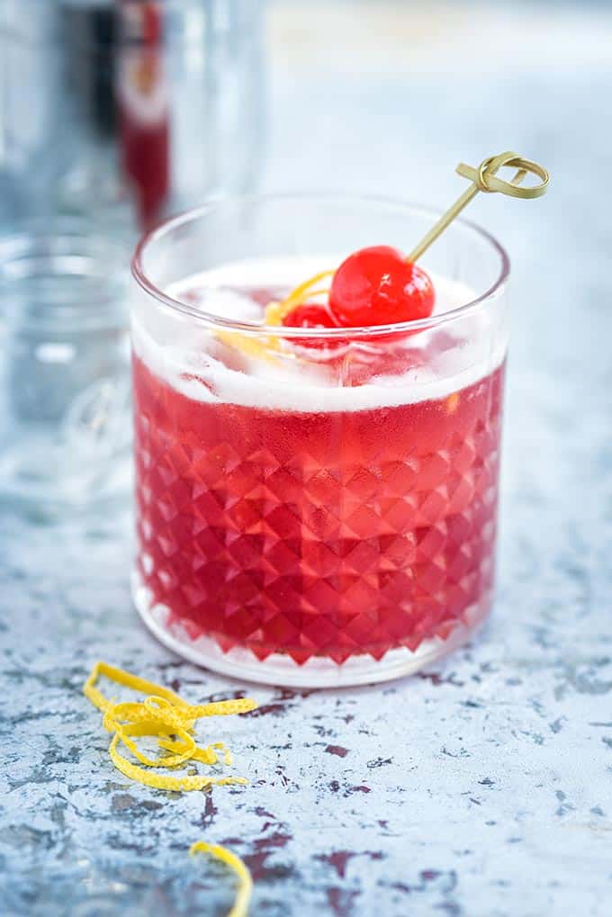 A cherry brandy and bourbon cocktail served on the rocks garnished with cocktail cherries