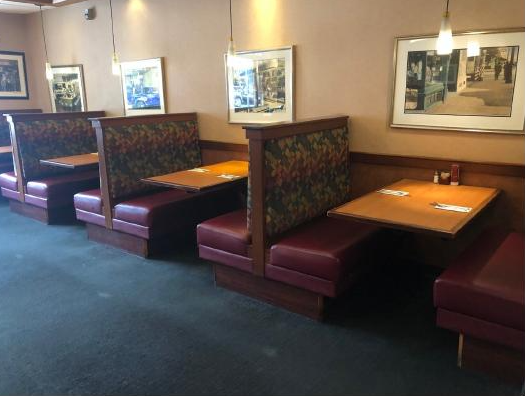 Three booths with multicolored seatbacks and maroon seats. Historical photos on wall.