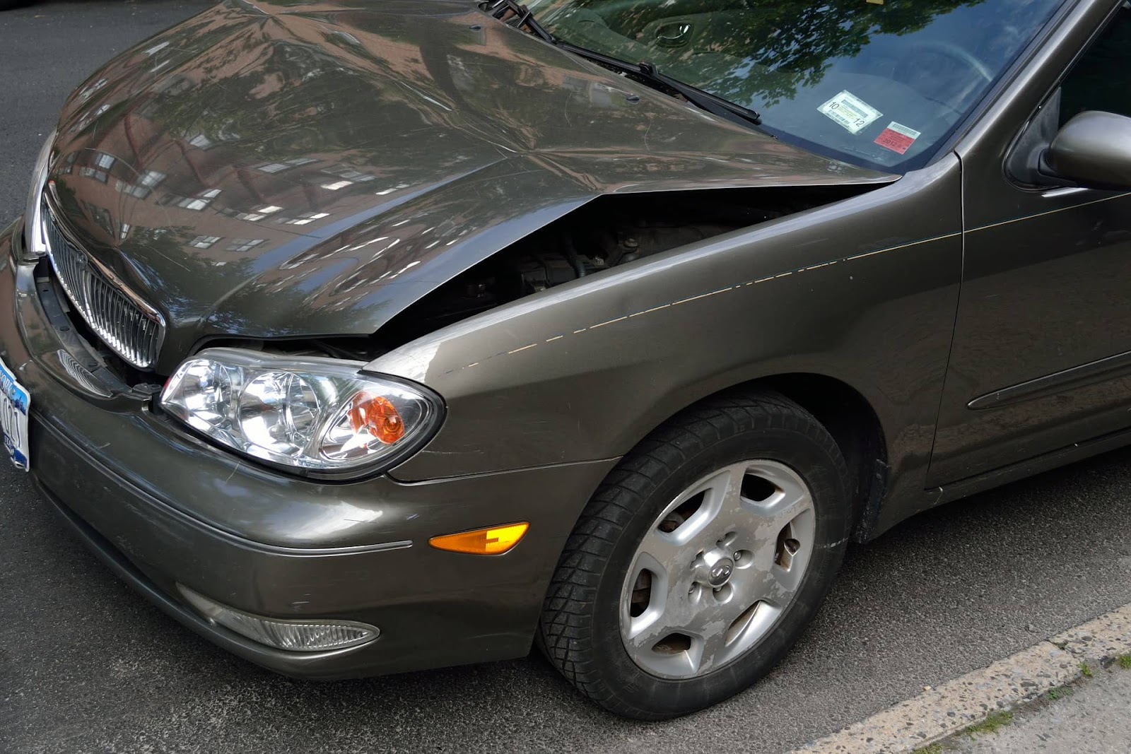 The front end of a car with a damaged fender and hood