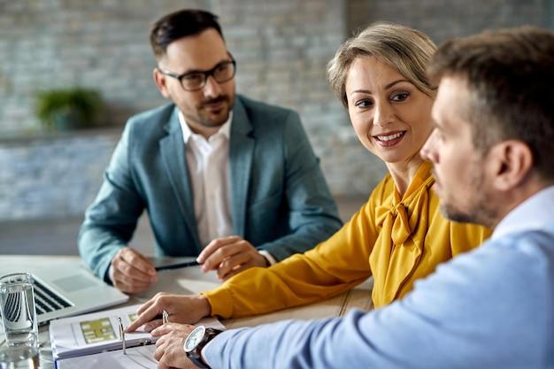 Premium Photo | Smiling woman and her husband analyzing blueprints while  having a meeting with real estate agent in the office