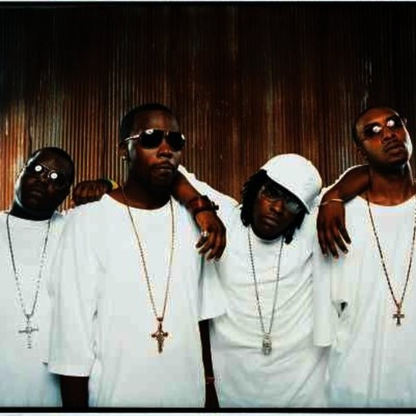 Dem Franchize Boys posing in white t-shirts, gold chains around their necks and dark sunglasses.