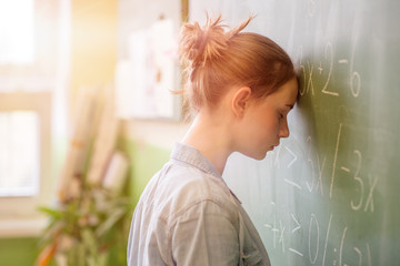 Child suffering from Math Anxiety with head against blackboard