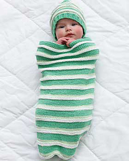 baby in a green and white striped cocoon and hat