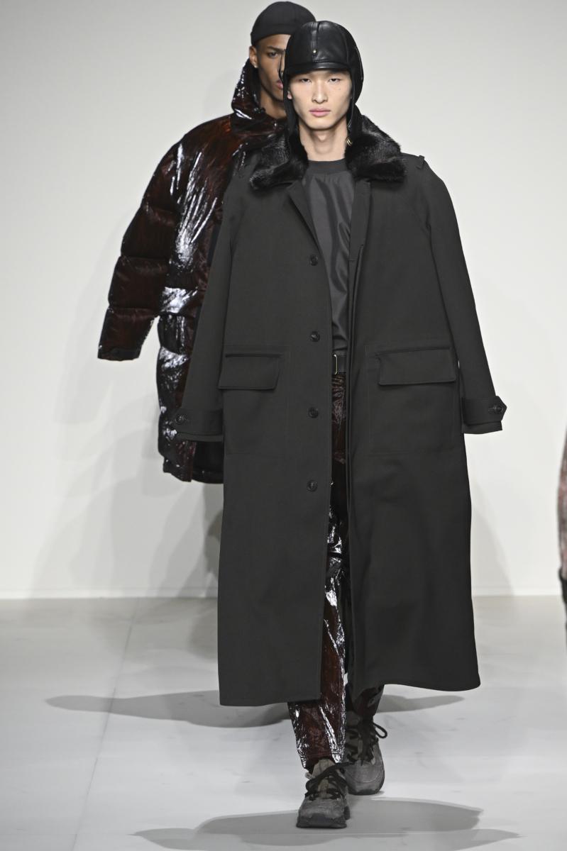 Un model pășește pe podium într-un palton negru din lână