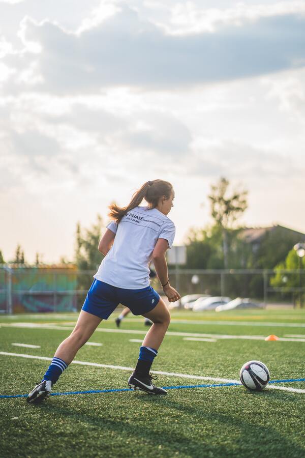 Foto tirada de uma mulher jogando futebol 