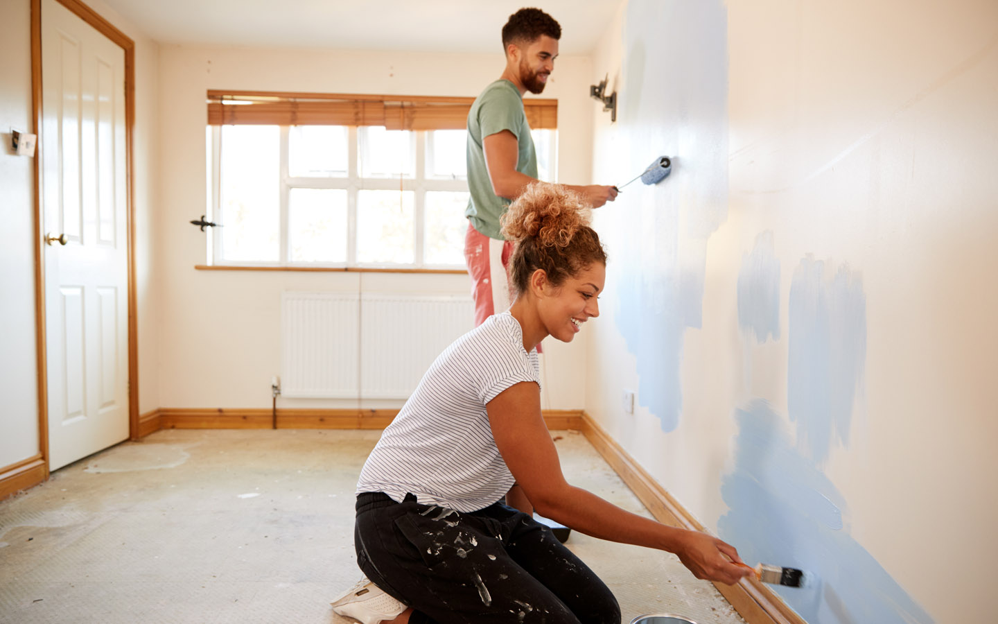 happy couple painting house walls