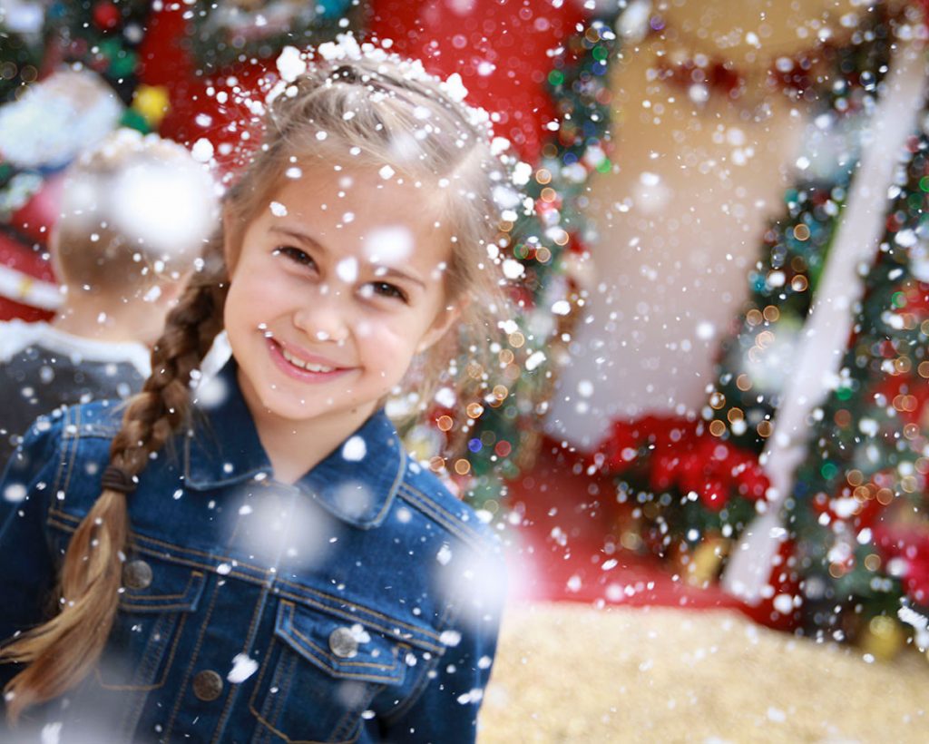 a girl smiling with a christmas tree in the background