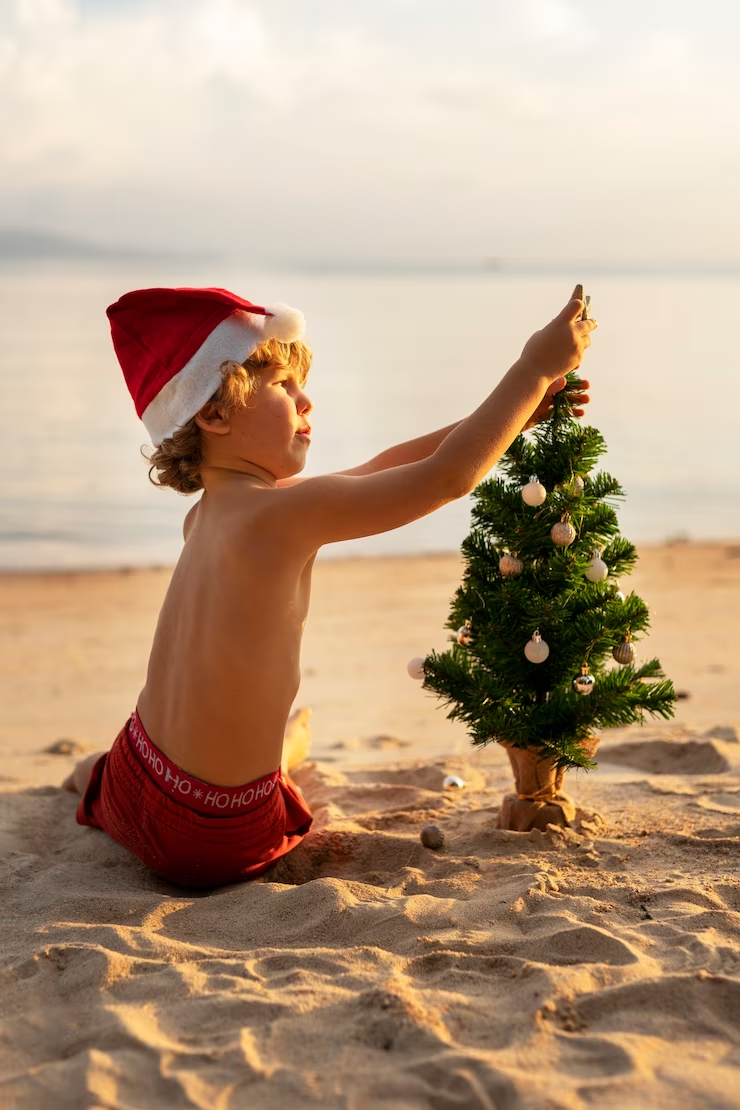 A child decorating a Christmas tree on the beach 
