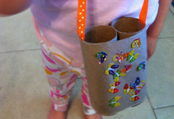 a child with their  toilet paper binoculars on their neck 