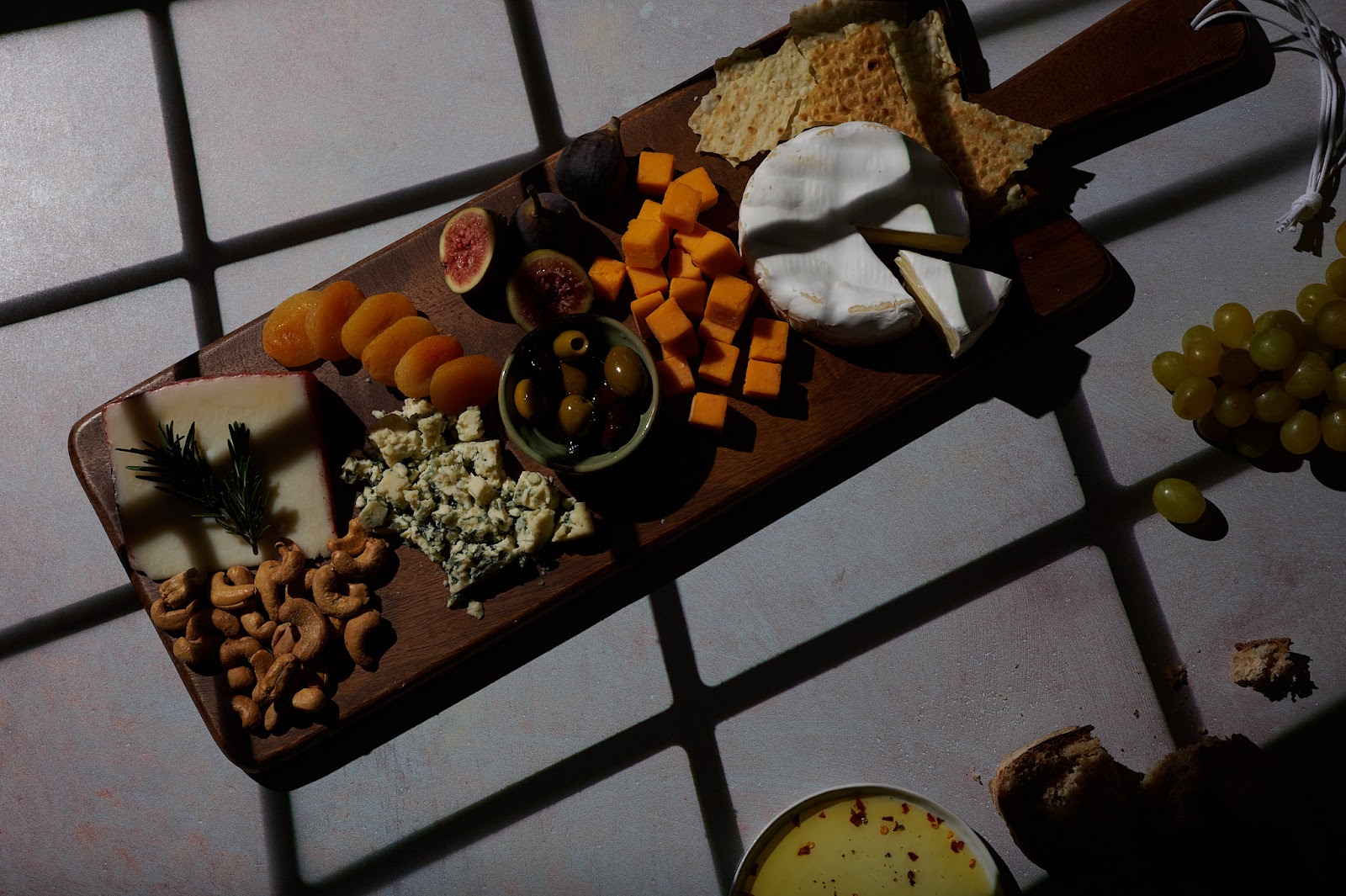Professional food photo of cheese board with dark window frame shadows across.