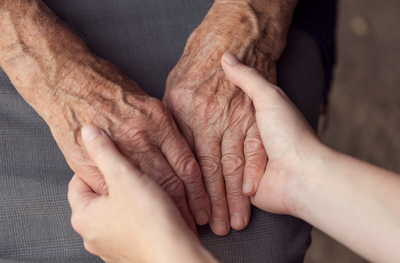 a young person holds a senior's hands in support