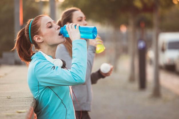 Tired sportswomen drinking water Premium Photo
