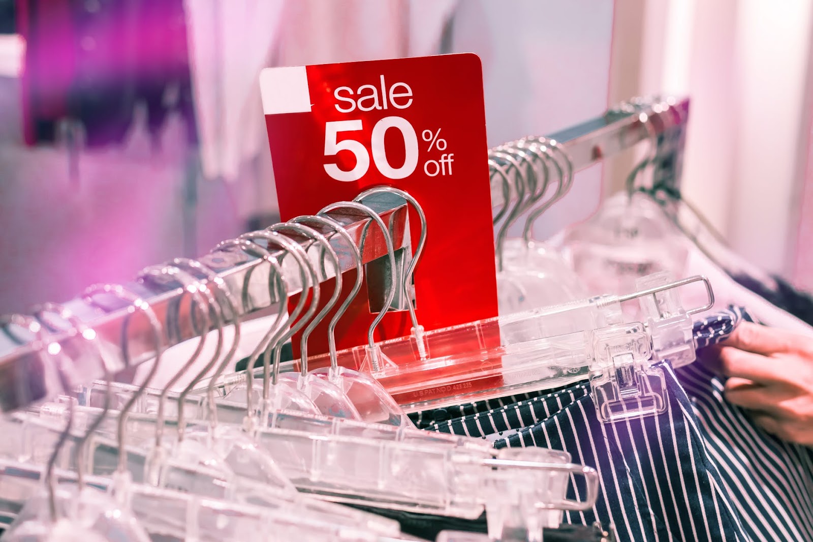 Apparel in hangers with "sale 50% off" placard. 