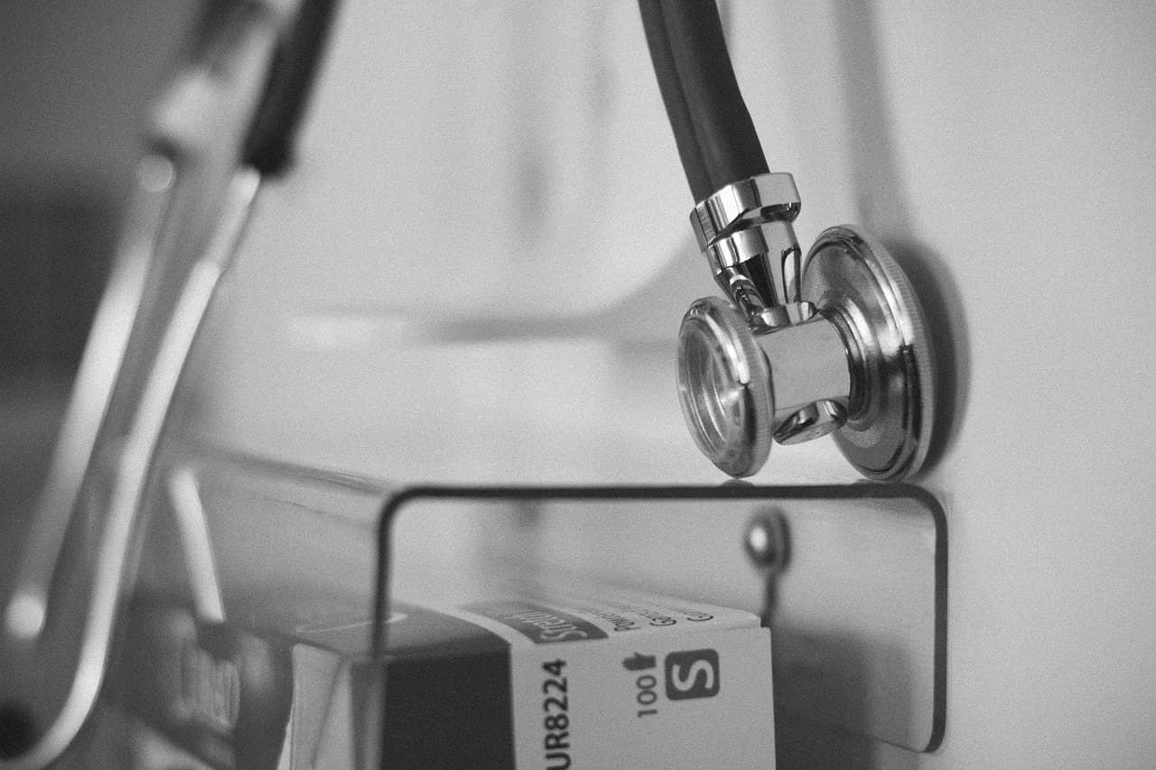 Immagine di uno stetoscopio e di una scatola di un farmaco in bianco e nero