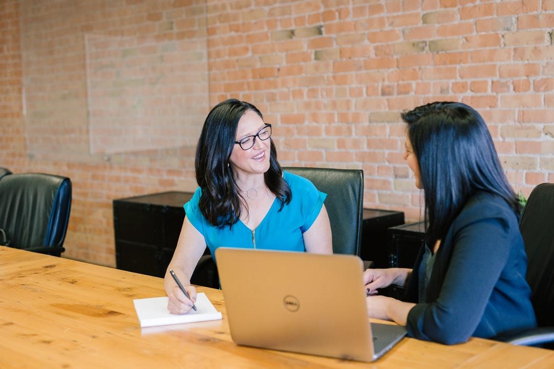 Two women sitting in a board room talking