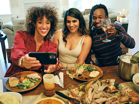 three friends having holiday dinner and taking a selfie to share with friends and family in their home. Therapy for mood disorders in Woodland Hills CA can help with coping with depression using cognitive behavioral therapy.  90077 | 91324 | 91364 | 91411 | 91436 