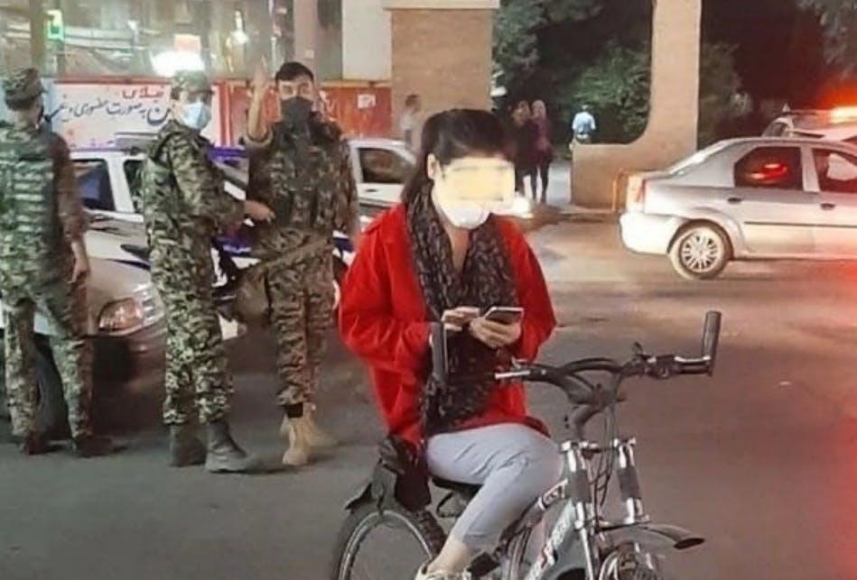 صحنه‌ای از جنبش انقلابی «زن، زندگی، آزادی» که دختری را روی دوچرخه بی حجاب در برابر ماموران سرکوب نشان می‌دهد