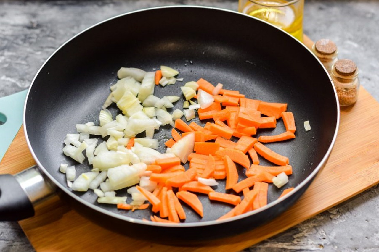 side dishes being prepared in a black frying pan with onions and carrots