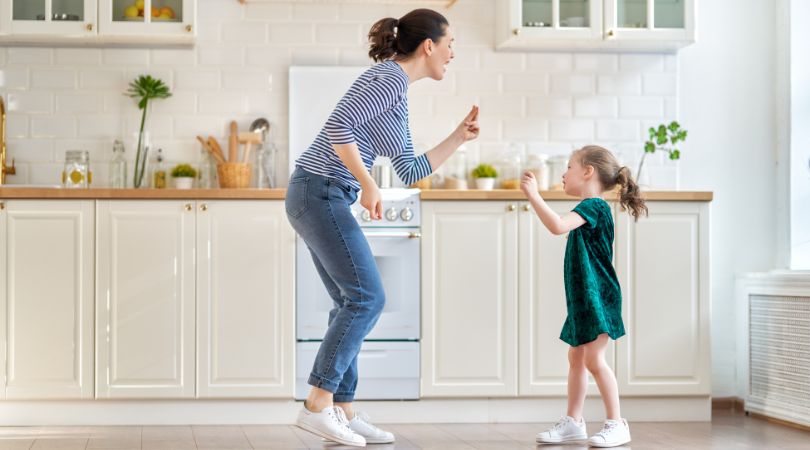 a woman and a child dancing in the kitchen
