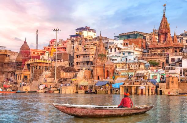 Hindu Sadhu Sitting On A Boat Overlooking Varanasi City Architecture At  Sunset Stock Photo - Download Image Now - iStock