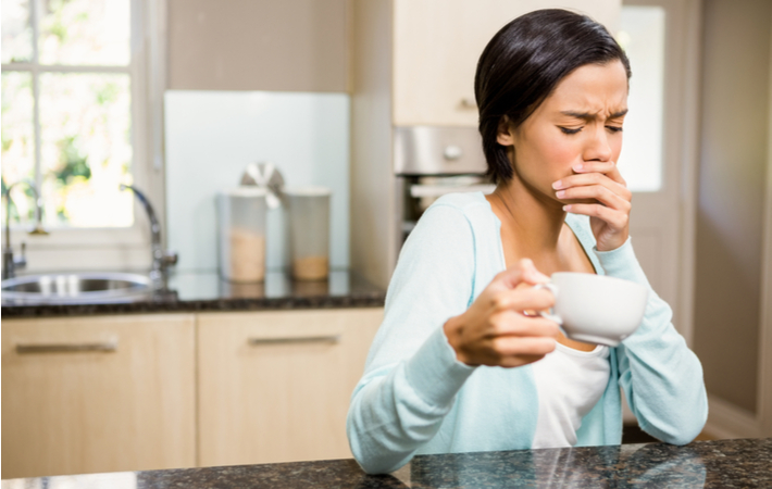 woman drinking a hot beverage and grimacing because of tooth sensitivity