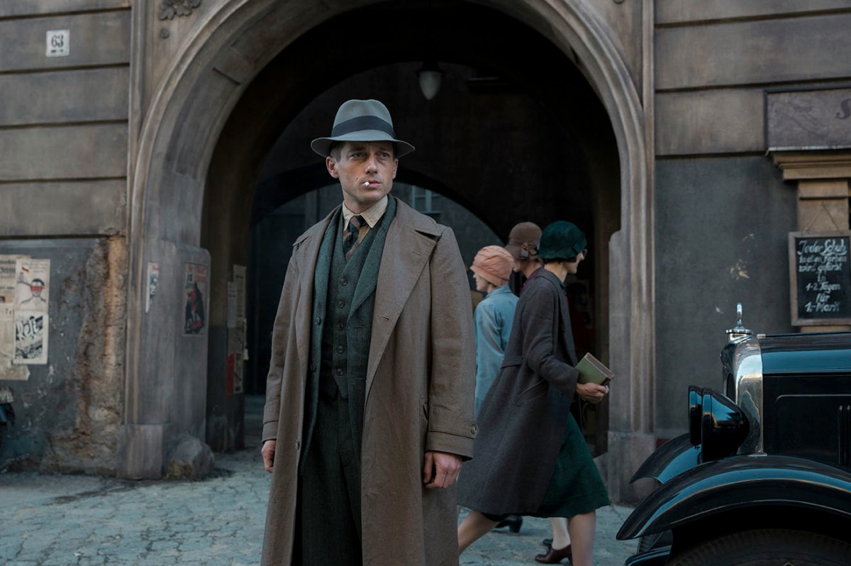 A still from Babylon Berlin showing protagonist Gereon Rath smoking a cigarette outdoors.