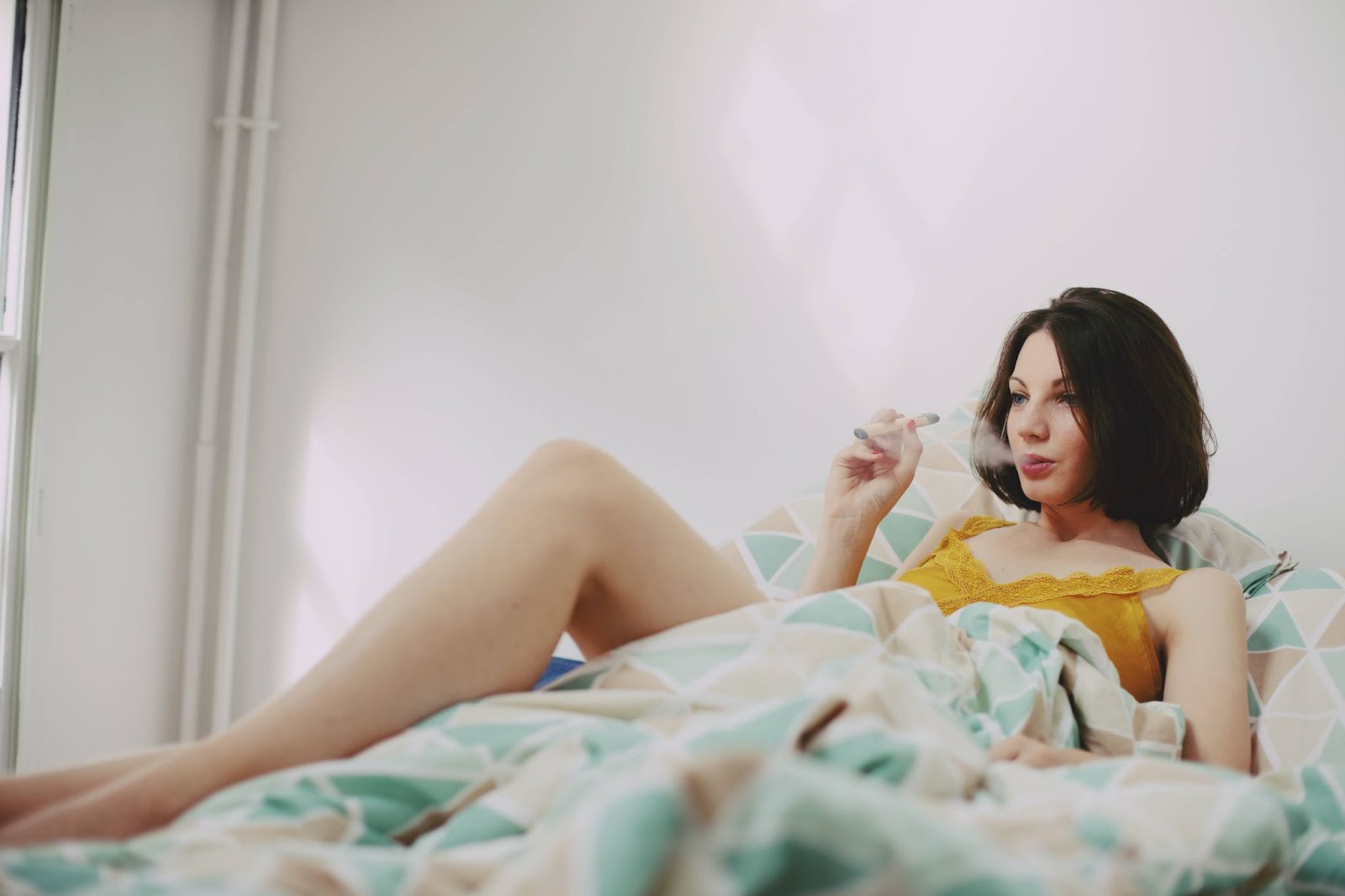 Woman vaping on a bed
