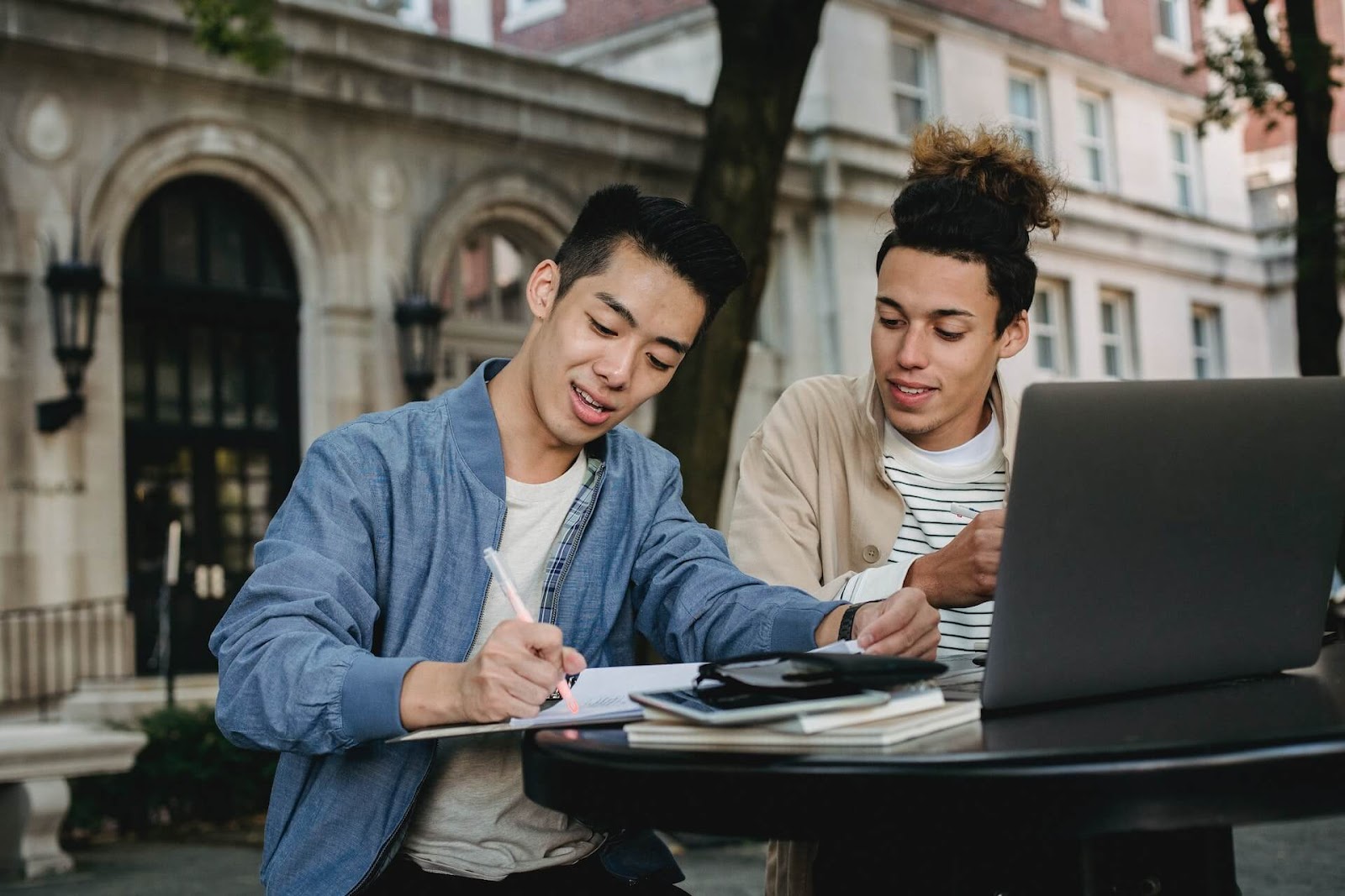 Two college students working at a table outside.