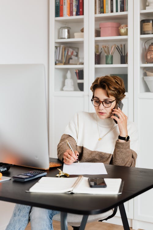Modern businesswoman in casual outfit talking on mobile in office
