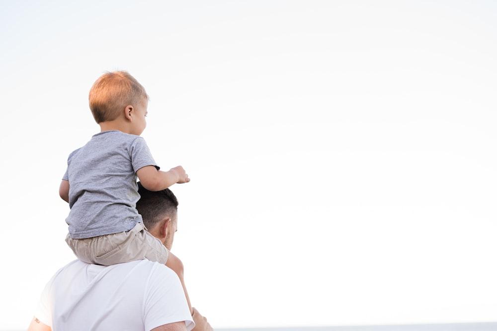 man in white shirt carrying boy