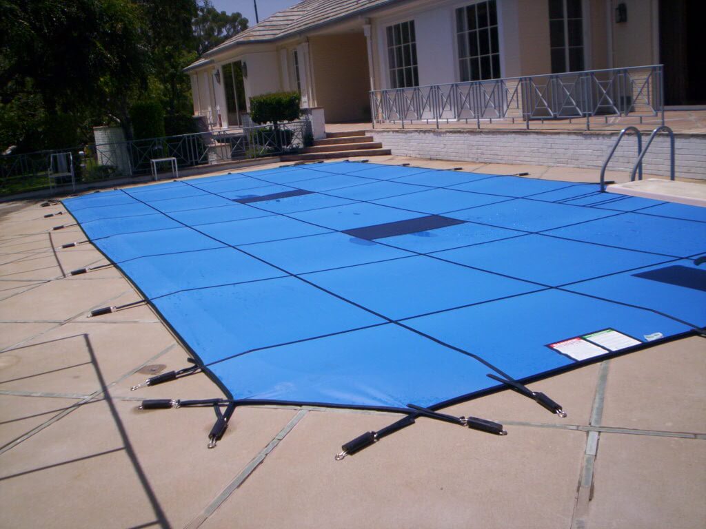 Blue winter pool safety cover installed on a swimming pool