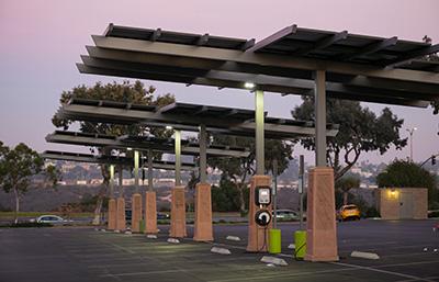 Solar-powered canopies cover an electric vehicle charging station in a public parking lot.
