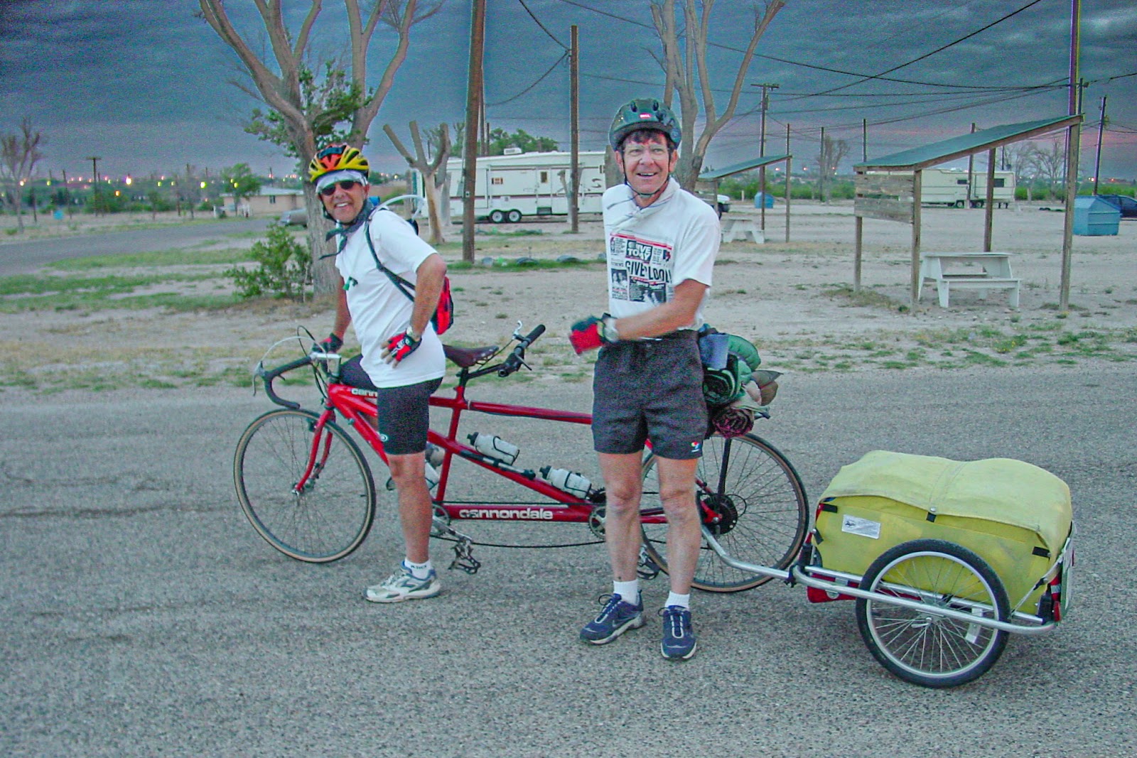 Two cyclists and a tandem bike with a two wheel trailer. 