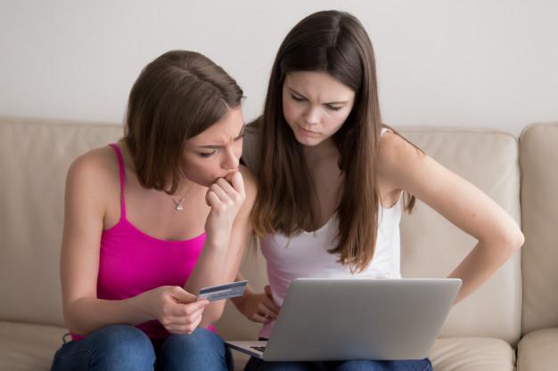 Woman friends in doubts as they choose goods online Free Photo