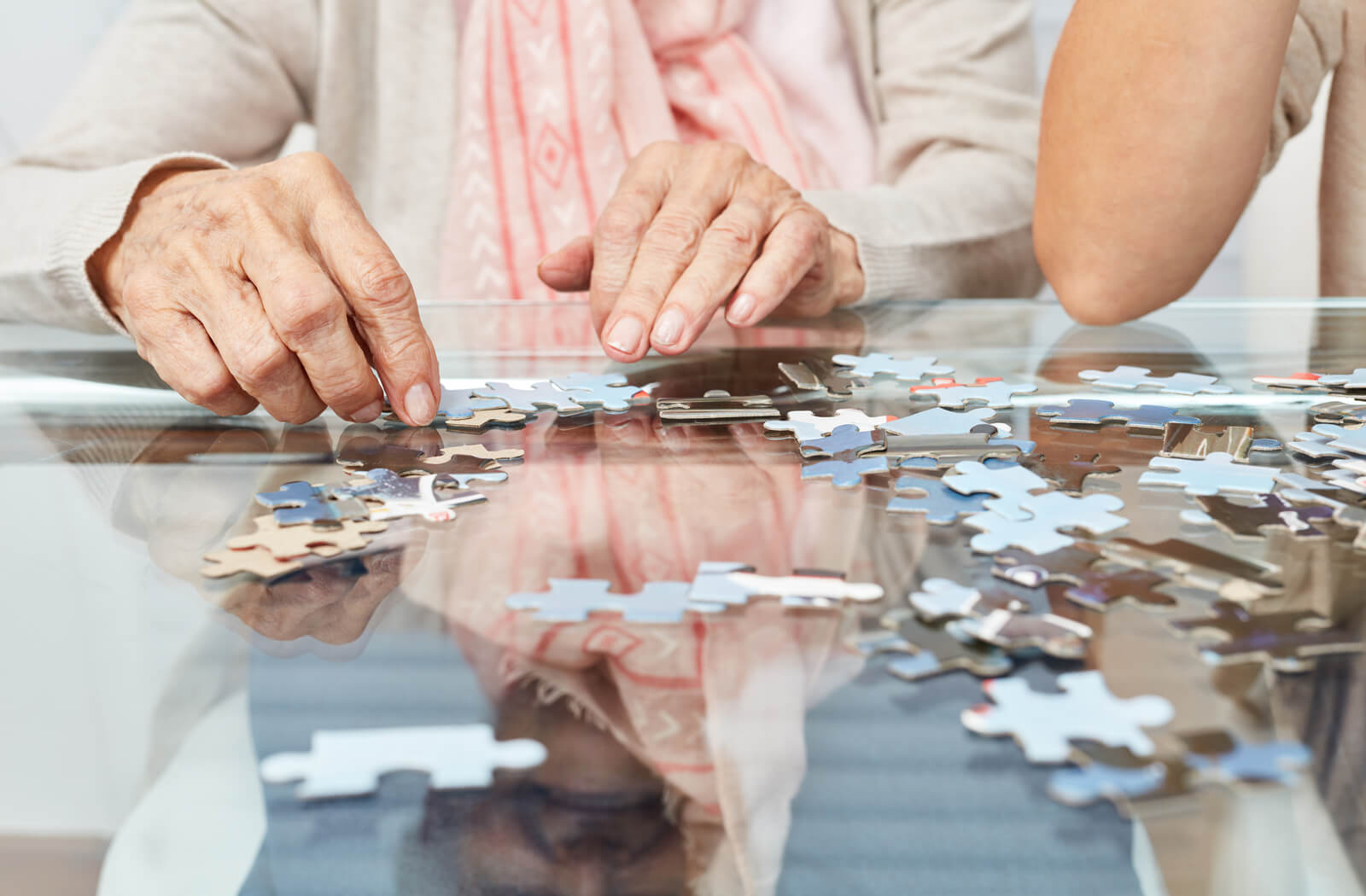 A close up of a senior's hands solving a jigsaw puzzle.