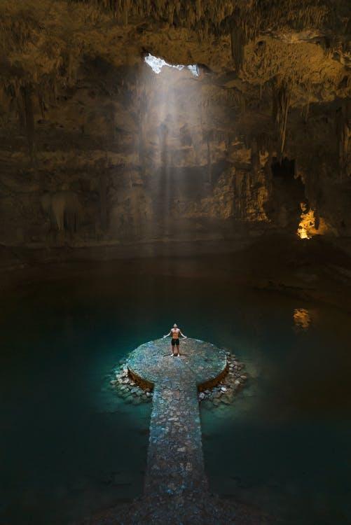 Free A Man Standing in the Middle of the Cave Surrounded with Water Stock Photo