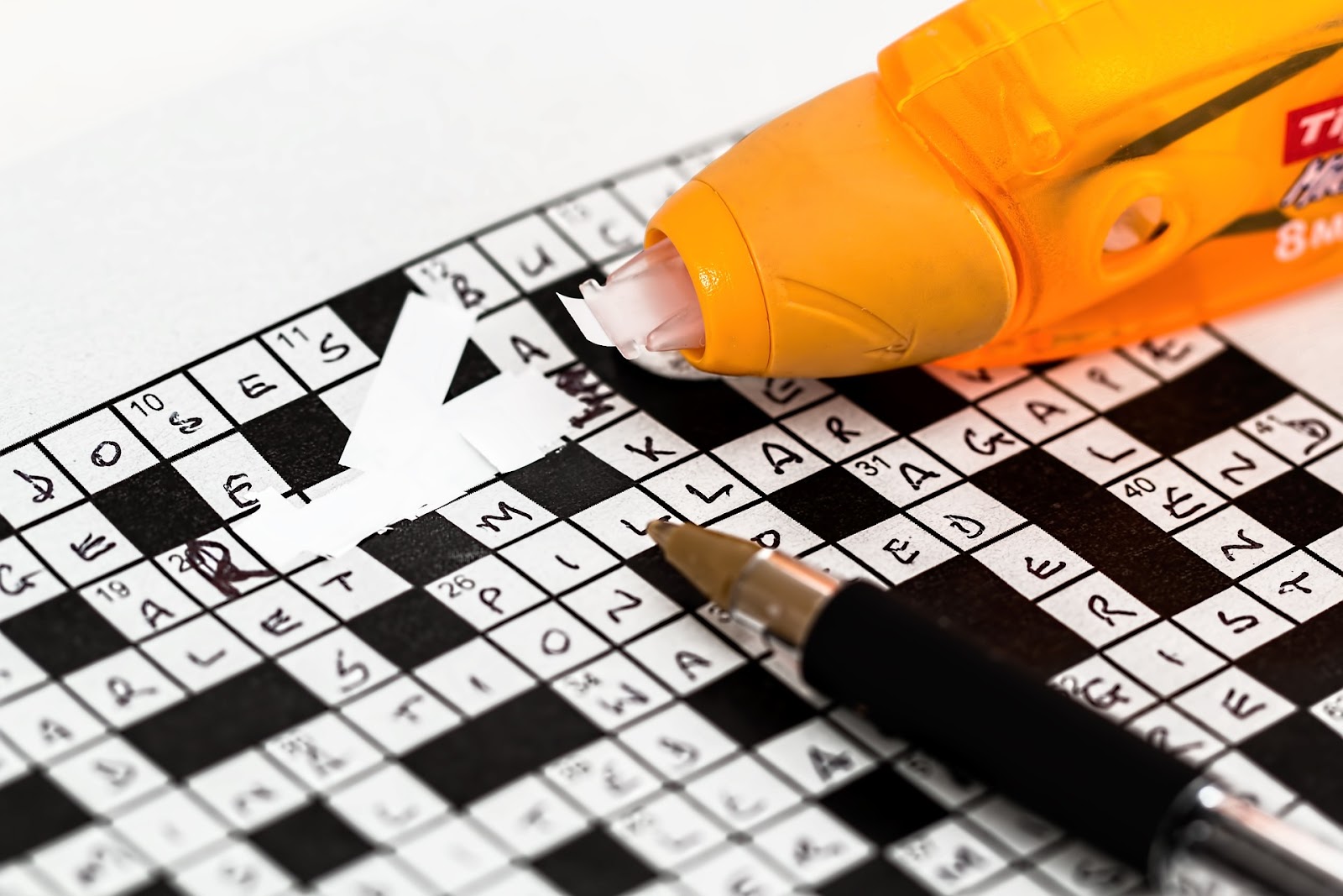A close up of a crossword puzzle that has had an error fixed with correction tape.